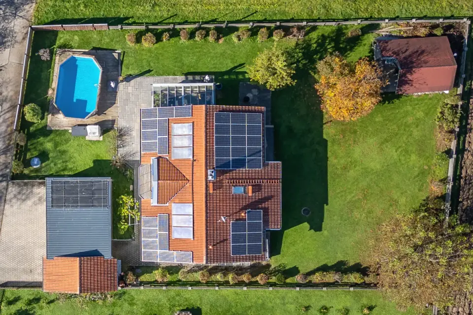 Senkrechte Drohnenaufnahme eines Hauses mit Solardach, Pool, Garage und großem Garten