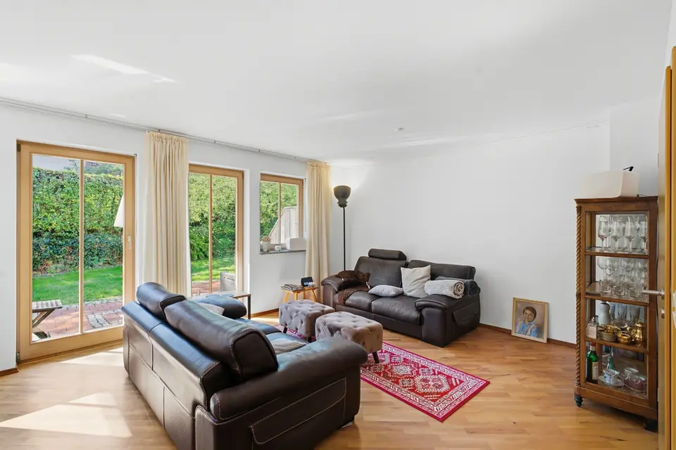 Wohnzimmer mit Ledersofas, Parkett und bodentiefen Fenstern zum Garten
