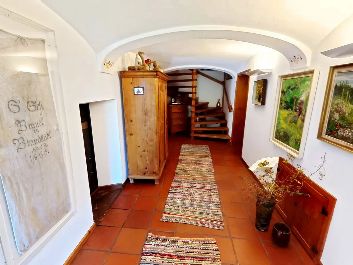 Startansicht eines 360-Grad-Rundgangs: Flur mit Gewölbedecke, Terrakottaboden, Bauernschrank und Holztreppe